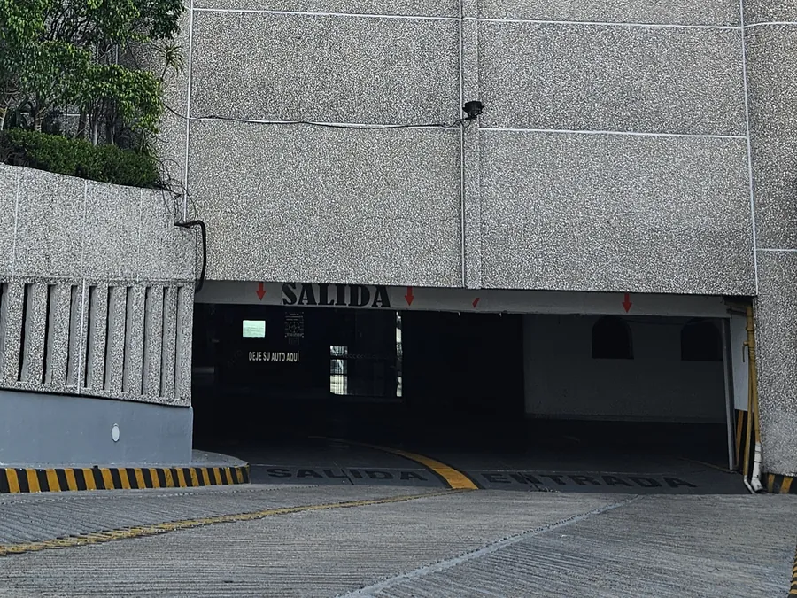 Rampa de acceso al estacionamiento del hotel, con SALIDA y ENTRADA pintadas en el pavimento y el letrero de salida sobre el vano