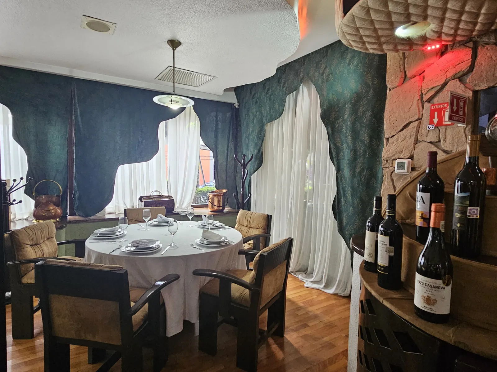 Mesa redonda de La Cava del Duque junto a la cortina blanca, con las botellas de vino a un lado