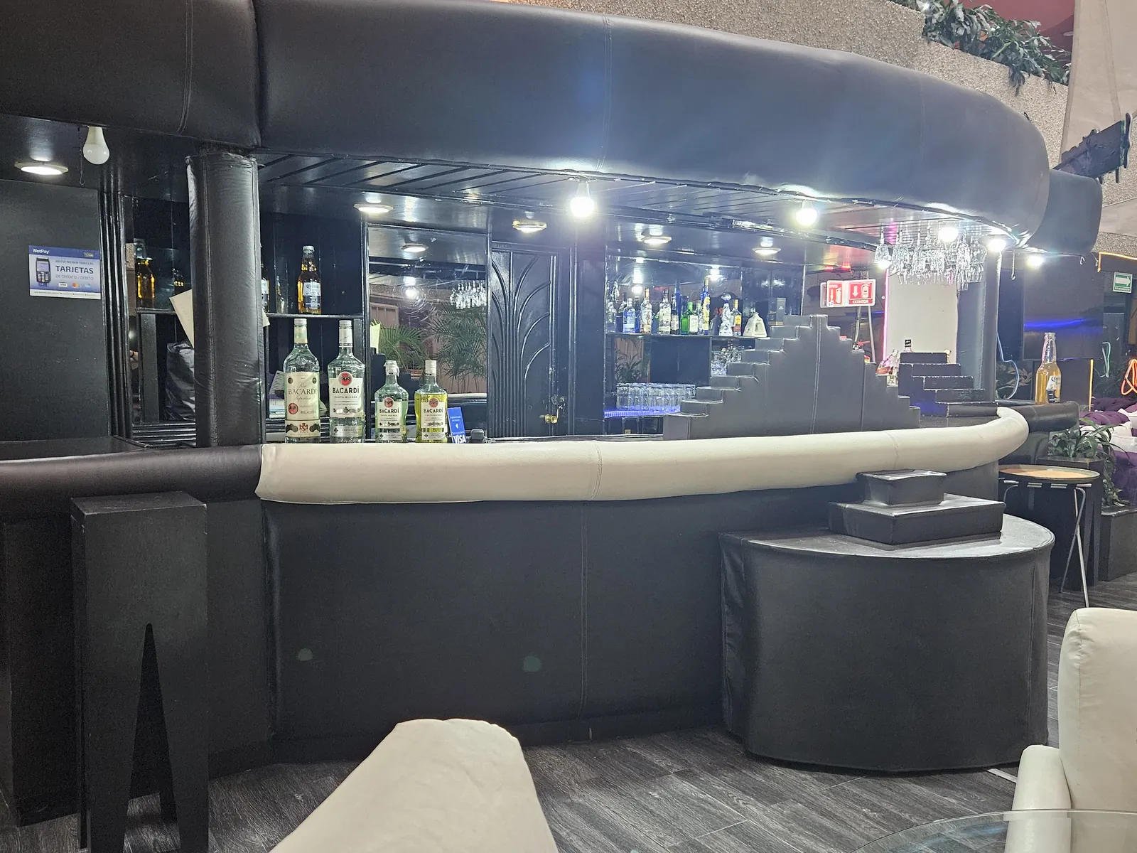 Barra del Lobby Bar Kon Tiki, con las botellas iluminadas al fondo y el pasamanos acolchado en primer plano