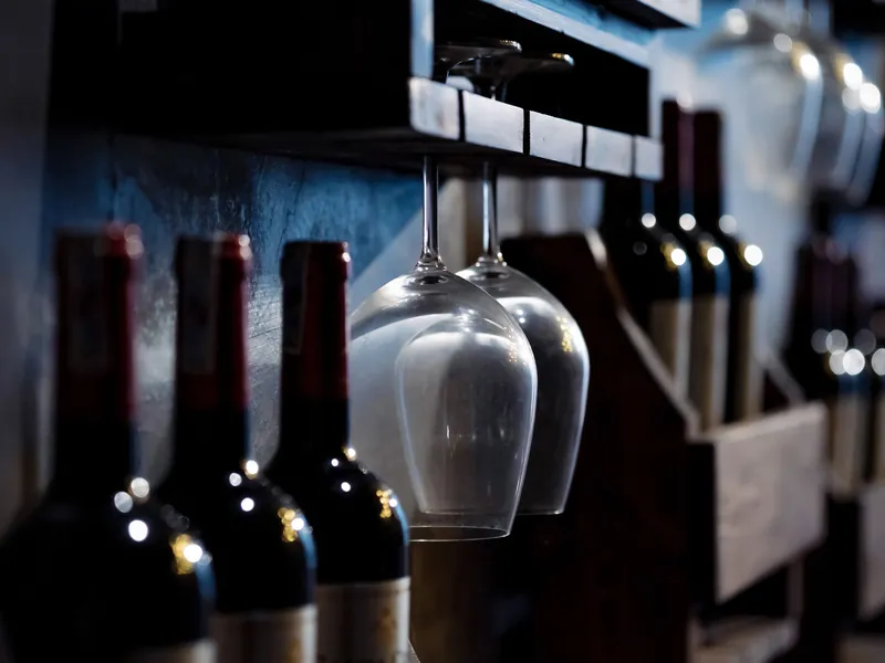 Imagen de referencia: botellas de vino tinto y una copa en una cava